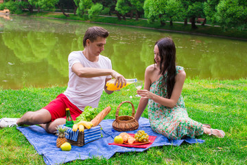 Young happy couple picnicking outdoors near the lake