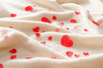 Many small red hearts on a fluffy beige plaid.