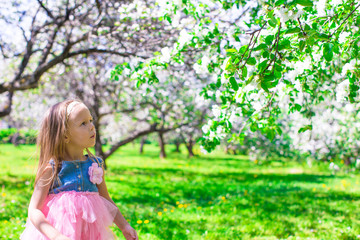 Plakat Adorable little girl in blooming apple tree garden on spring day