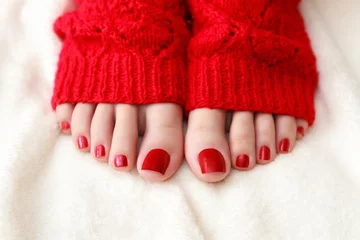 Rolgordijnen Female feet with a pedicure in red socks © perfectlab