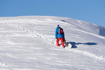 Fototapeta na wymiar Snowboarder climbing a snowy mountain