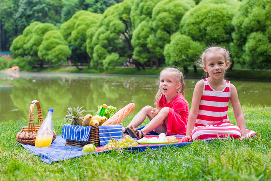 Adorable little girls picnicing in the park at sunny day