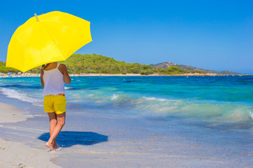 Little adorable girl with big yellow umbrella on tropical beach