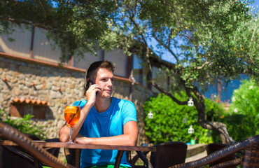 Young man in outdoor cafe talking on cellphone