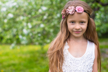 Portrait of little adorable girl in blossoming apple garden