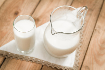 Jug,glass of milk,delicate cloth on old wooden table.top view