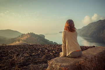 Woman sitting on unusual rock at sunrise