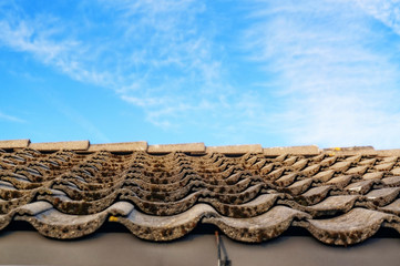 Roof with gray tiles on the tabs on background of blue sky