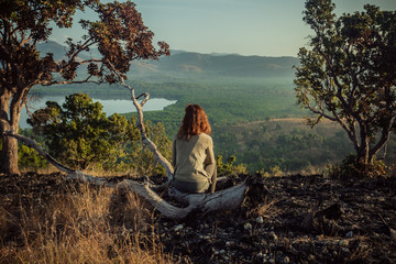 Woman sitting on a hill at sunrise