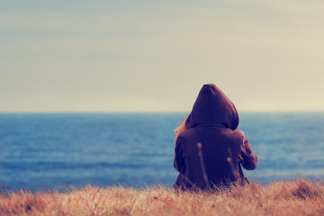 Girl sitting on a meadow with a beautiful sea/ocean view.