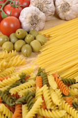 Selection of different spaghetti and pasta with garlic tomato and olives ingredients for cooking photo