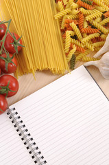 Selection of different spaghetti and pasta with blank cookbook recipe book or note book ingredients for cooking photo