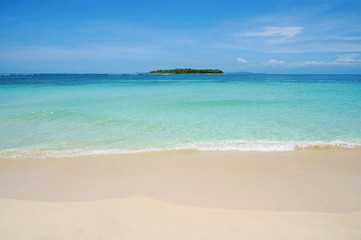 Fototapeta na wymiar Beach sand with tropical island at the horizon