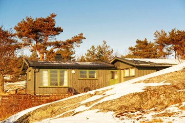 Fototapeta na wymiar Green cottage hidden among rocks in winter
