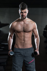 Fototapeta na wymiar Young Man Exercising Biceps With Dumbbells