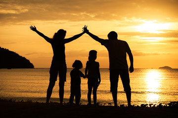 Silhouette of happy family who playing on the beach at the sunse