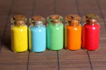 Bottles with colorful dry pigments on bamboo mat background