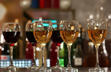 Glasses of wine on counter and bar on background