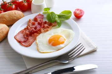 Bacon and eggs on color wooden table background