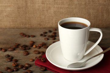Cup of coffee with beans on rustic wooden background