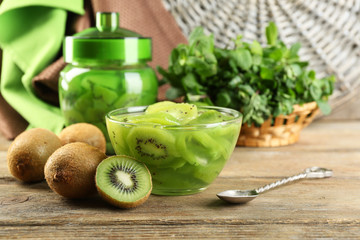 Tasty kiwi jam in glass bowl on wooden background