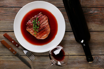 Grilled steak in wine sauce with bottle of wine