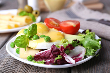 Toast with egg Benedict and avocado on plate on wooden table