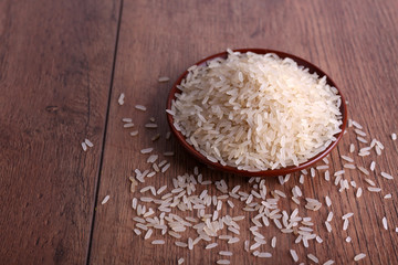 Grain of rice on plate on wooden background