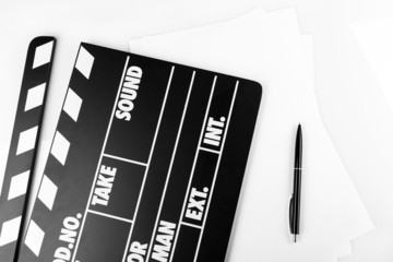 Movie clapper with sheets of paper and pen on white background
