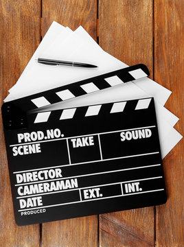 Movie clapper with sheets of paper and pen
