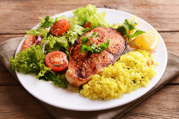 Tasty baked fish with rice on plate on table close-up