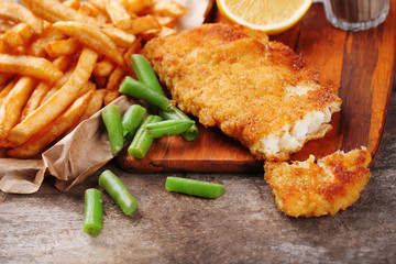 Breaded fried fish fillet and potatoes with asparagus and lemon