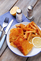 Breaded fried fish fillets and potatoes with with sliced lemon