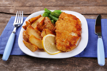 Breaded fried fish fillet and potatoes with asparagus and lemon