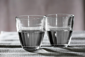 Two glasses of water on table on light background