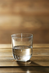 Glass of clean mineral water on rustic wooden background