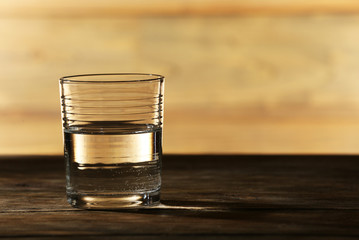Glass of clean mineral water on surface and background