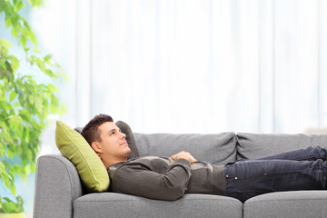 Fototapeta premium Relaxed young man lying on a sofa at home