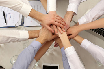 United hands of business team on workspace background top view