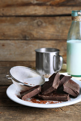 Metal mug and glass bottle of milk with chocolate chunks and