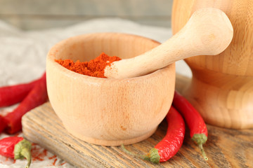 Ground red pepper in mortar with chili pepper