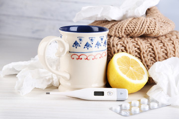 Hot tea for colds, pills and handkerchiefs on table close-up