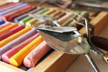 Colorful chalk pastels in box with palette knifes close up