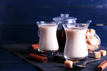 Black tea with milk in glasses and teapot with lump sugar