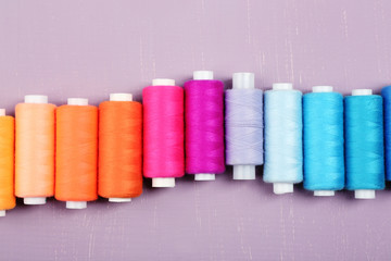Multicolor sewing threads on wooden background