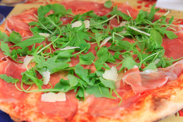 Italian pizza with parmesan, rucola and prosciutto