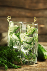 Glasses with fresh organic cucumber water on wooden table