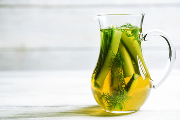 Glass ewer with fresh organic cucumber water on wooden table