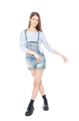 Young fashion girl in jeans overalls posing isolated