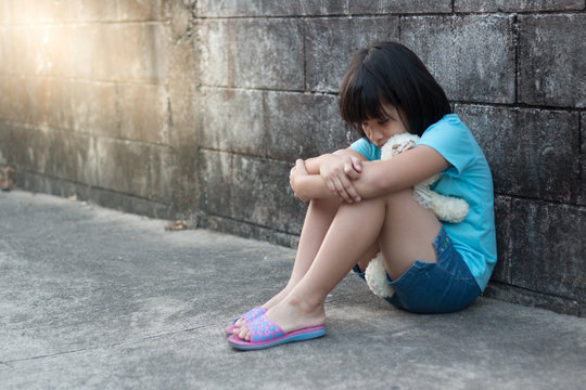 Portrait Of A Sad And Lonely Asian Girl Against Grunge Wall Back